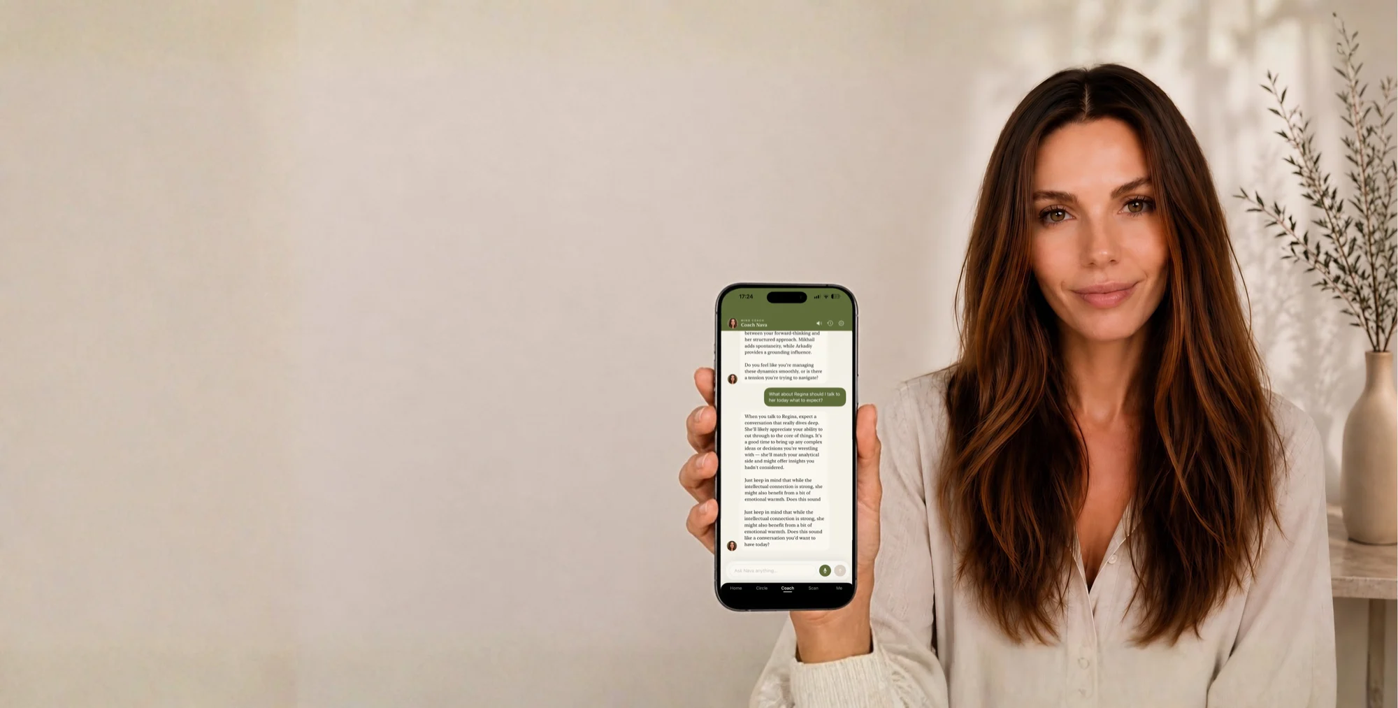 A woman holding a phone showing the Coach Nava chat.